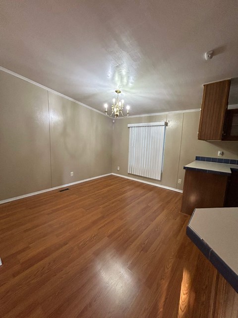 an empty living room with wood floors and a window