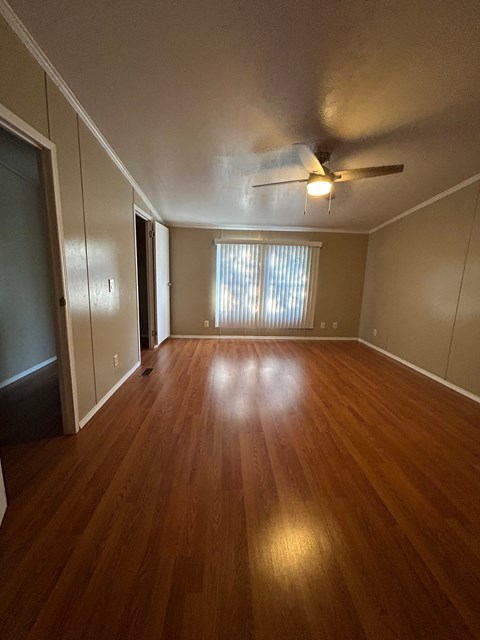 an empty living room with wood floors and a ceiling fan