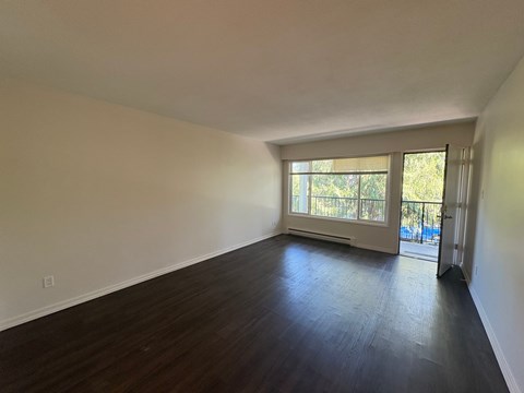 A room with wooden floors and a window with blinds.
