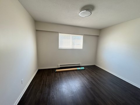 A room with a window and a wooden floor.
