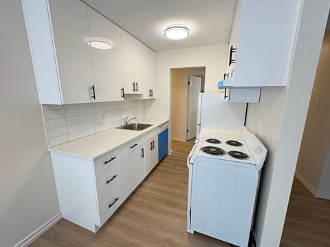 A small kitchen with a white stove and cabinets.