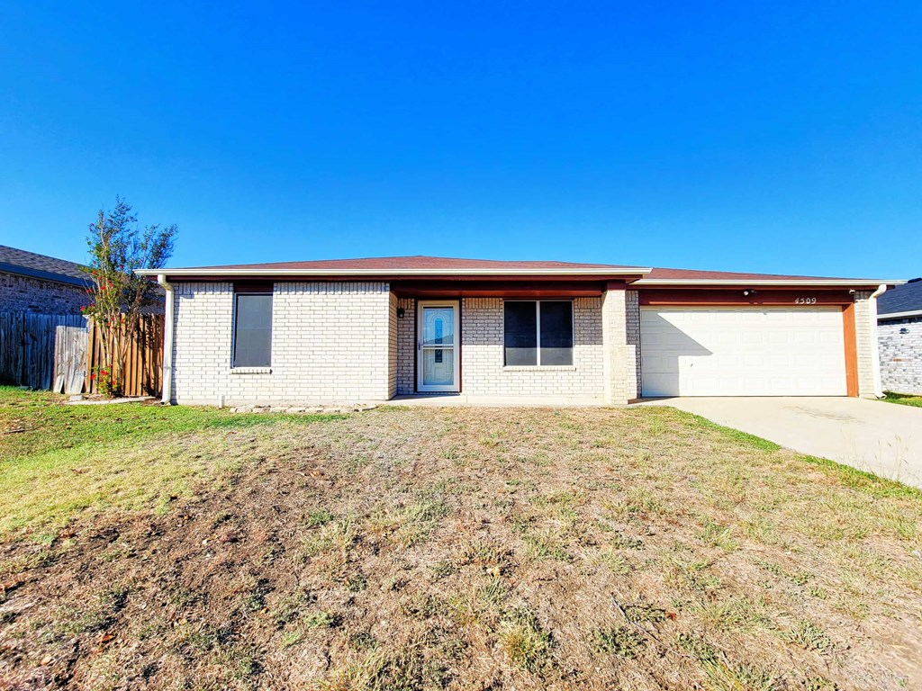 a white brick house with a driveway and a garage door