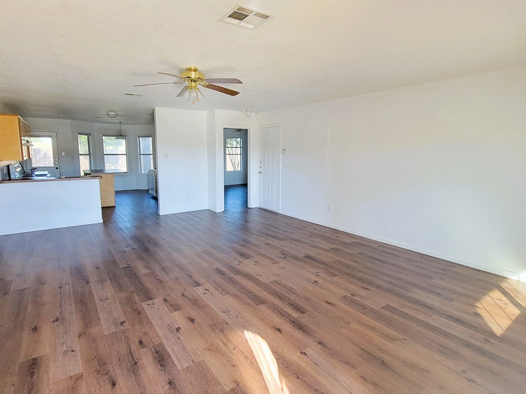 an empty living room with hardwood floors and a ceiling fan