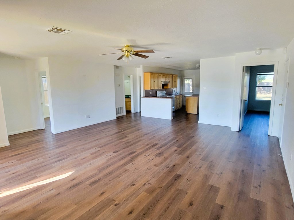 an empty living room with wooden floors and a ceiling fan