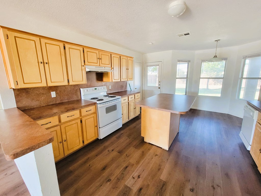 an empty kitchen with wood floors and wooden cabinets