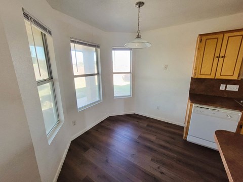 an empty kitchen with hardwood floors and a window