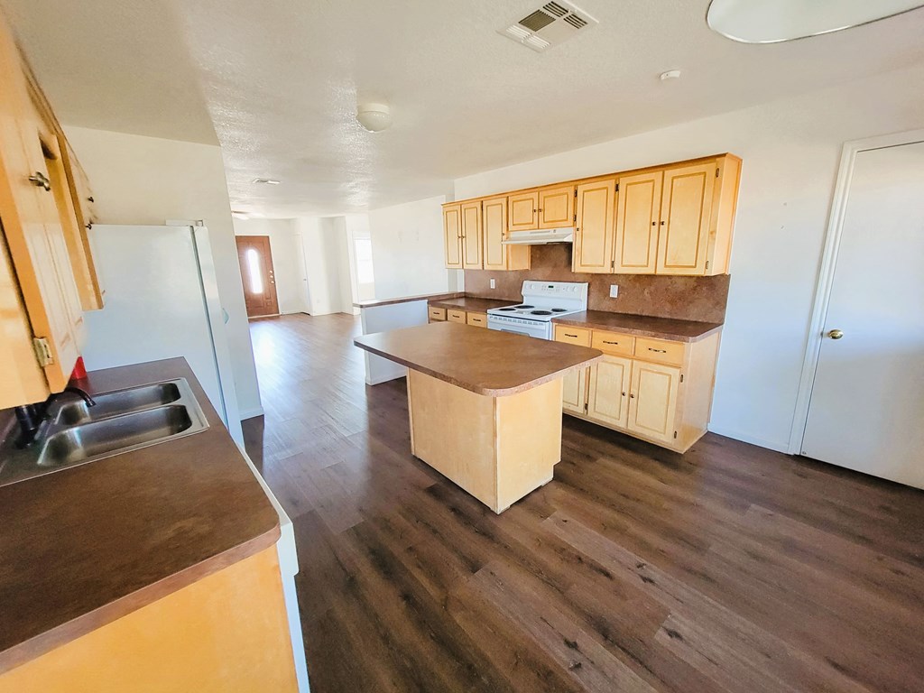 an empty kitchen with wood flooring and wooden cabinets