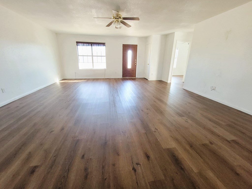 an empty living room with wooden floors and a ceiling fan