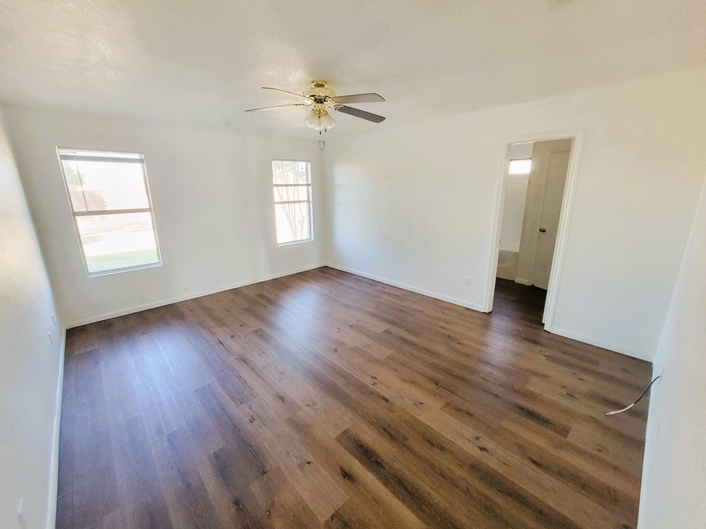 an empty living room with wooden floors and a ceiling fan