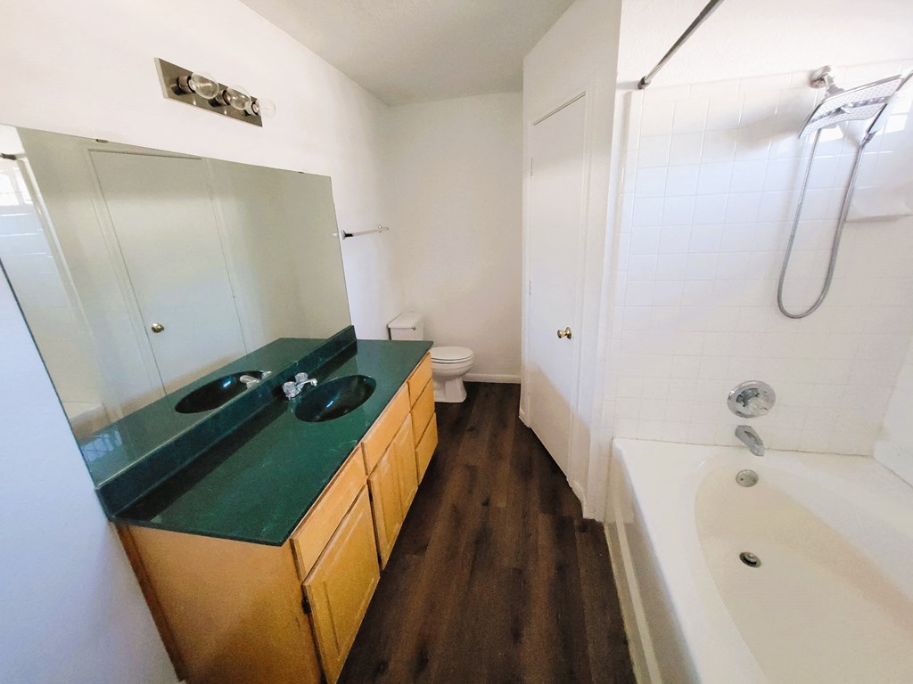 a bathroom with a green counter top and a tub and a sink and a shower