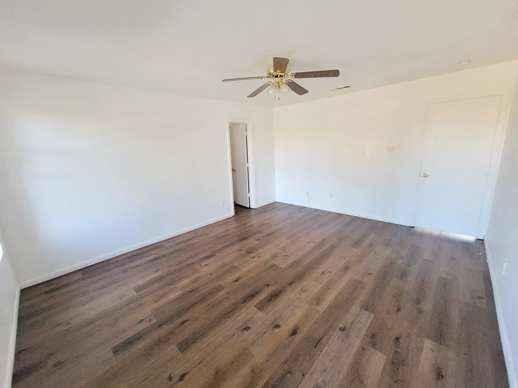 an empty living room with white walls and a ceiling fan