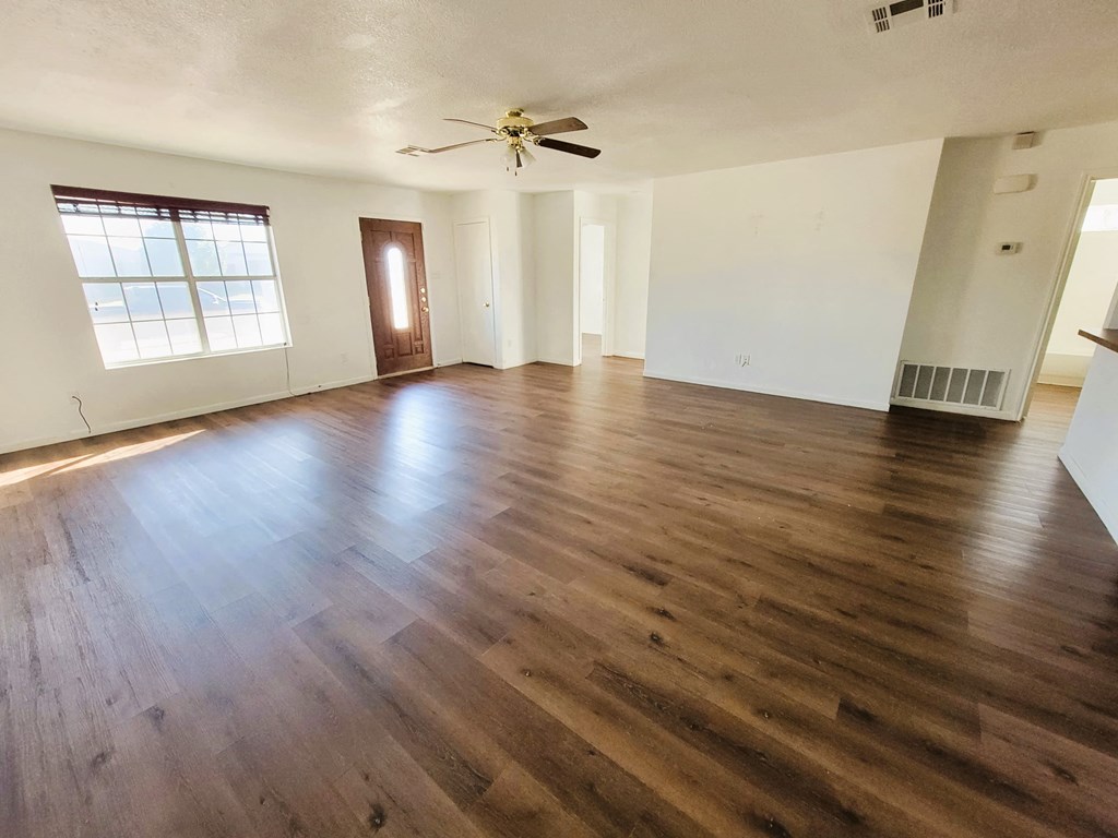 an empty living room with hardwood floors and a ceiling fan