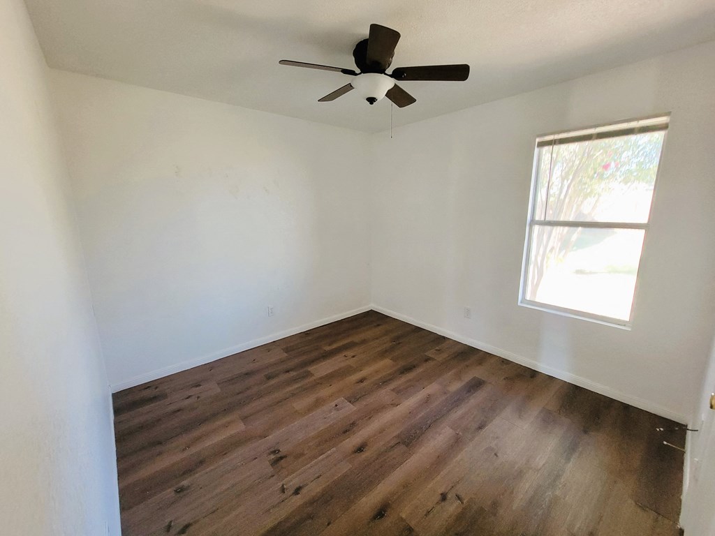 an empty room with wooden floors and a ceiling fan
