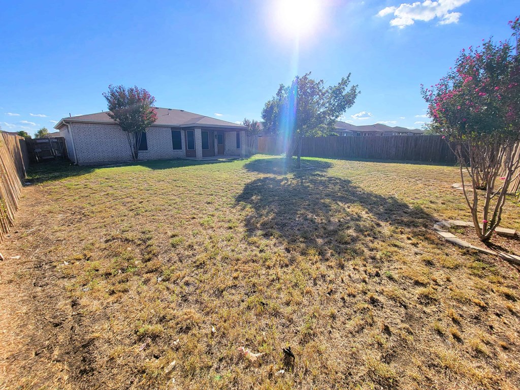 a backyard with a house and the sun shining over the grass