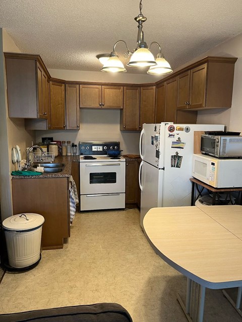 a kitchen with white appliances and wooden cabinets and a table