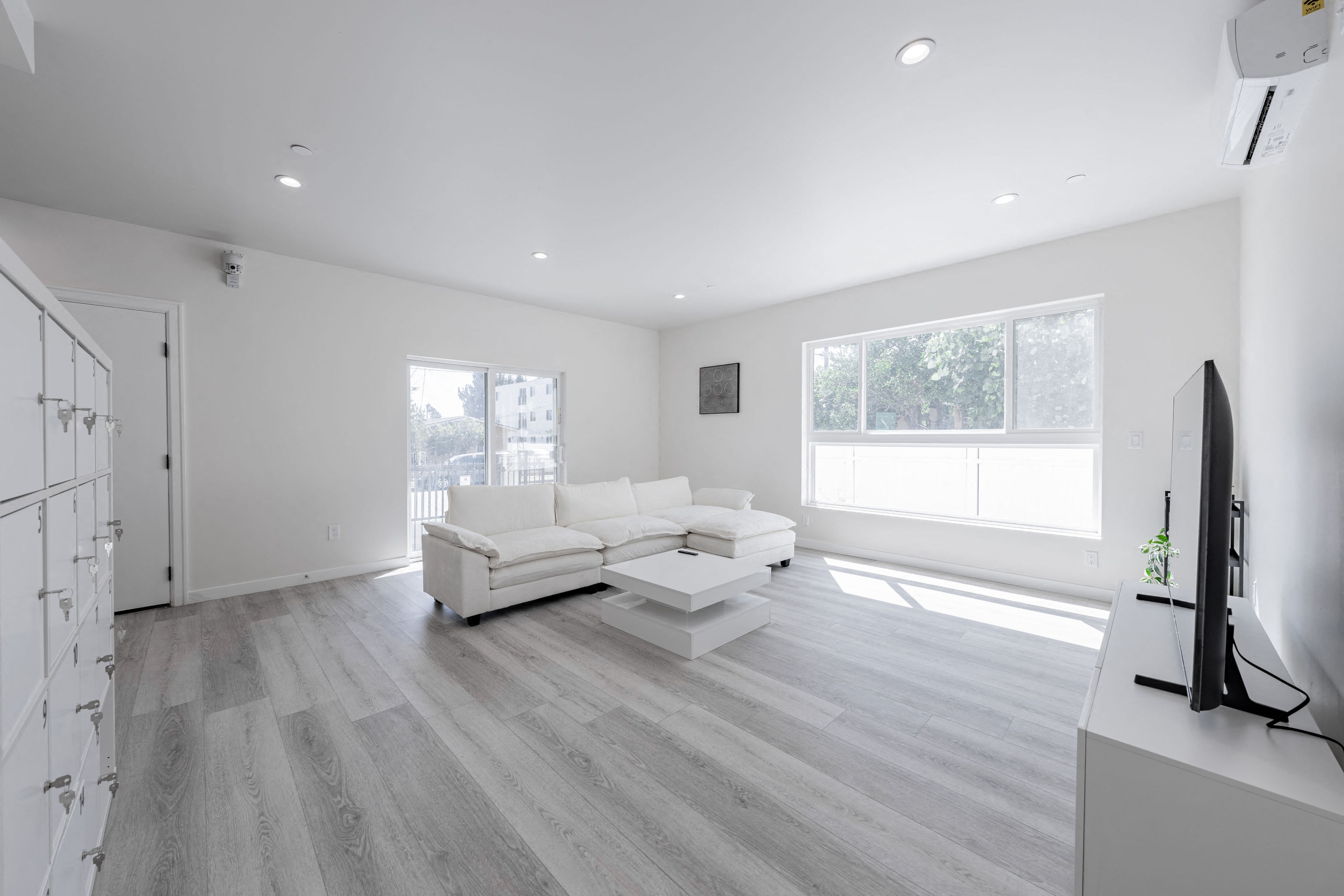 a white living room with a white couch and a tv