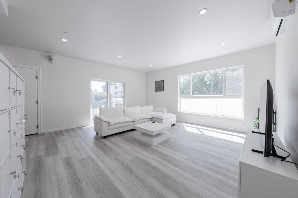 a white living room with a white couch and a tv