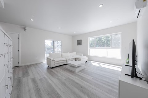 a white living room with a white couch and a tv