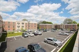 A parking lot with cars and apartment buildings in the background.