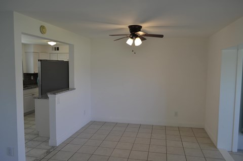 an empty living room with a ceiling fan and a tiled floor