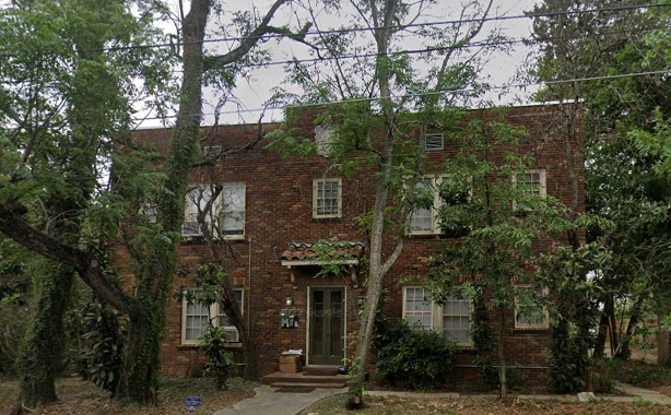a red brick house with trees in front of it