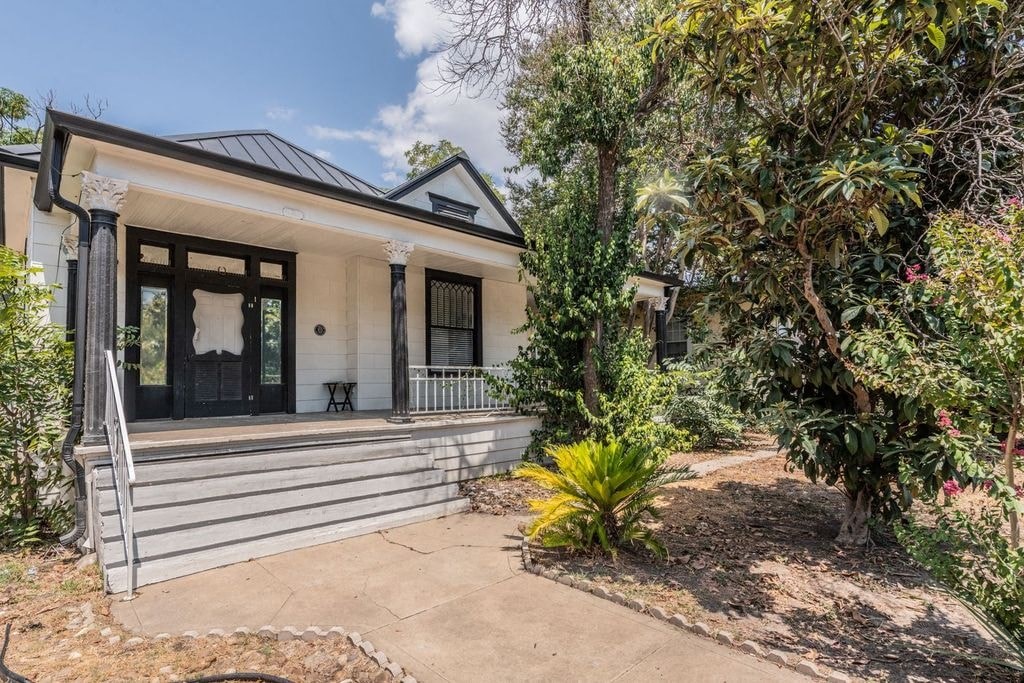 the front of a house with trees and a sidewalk