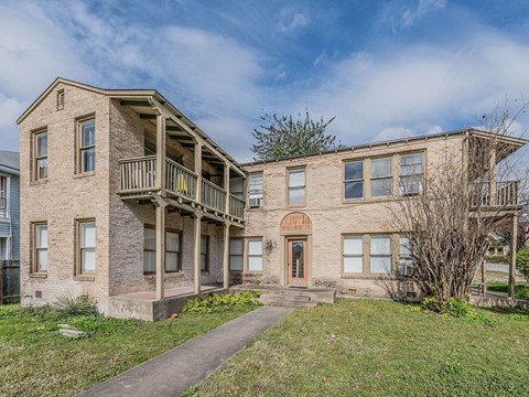 a brick apartment building with a balcony and a sidewalk