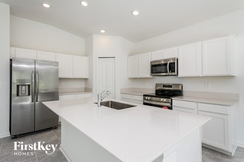 a white kitchen with stainless steel appliances and white counter tops