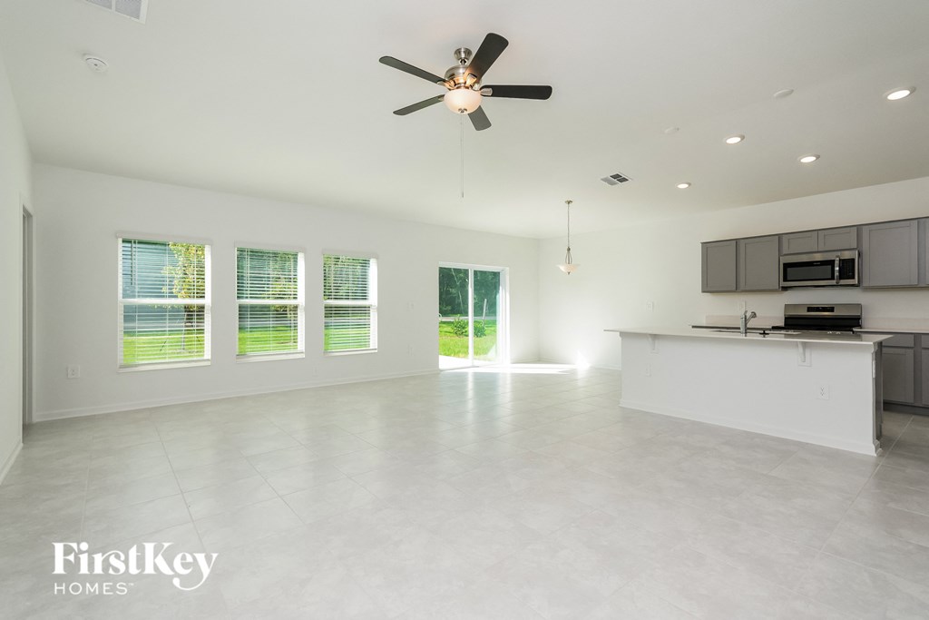an empty kitchen and living room with a ceiling fan