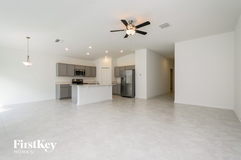 an empty living room and kitchen with a ceiling fan
