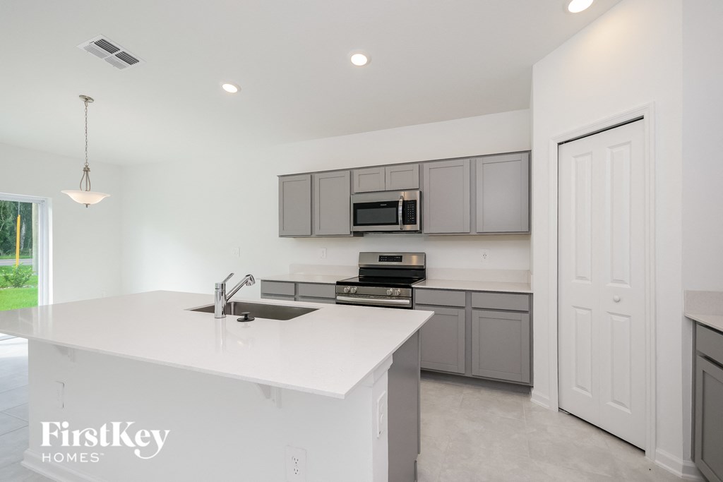 a white kitchen with gray cabinets and a white counter top