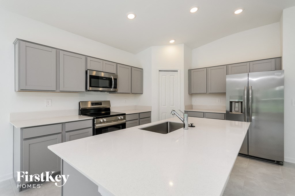 a large white kitchen with stainless steel appliances and white counter tops