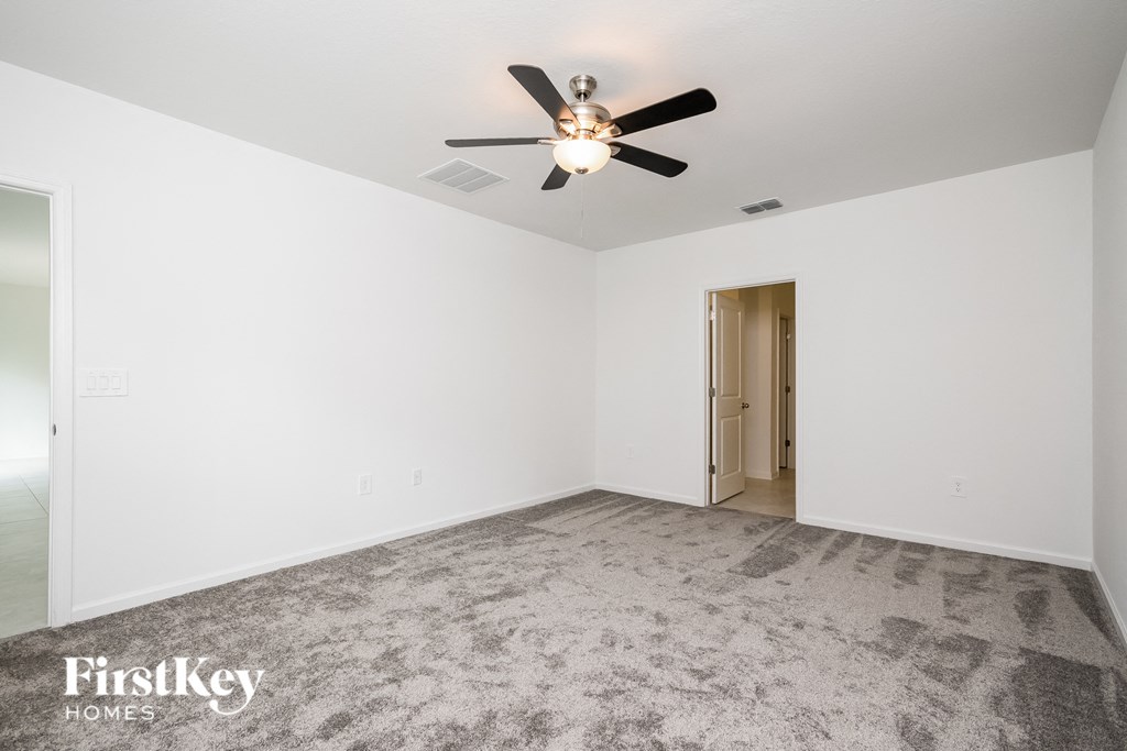 a empty living room with white walls and a ceiling fan