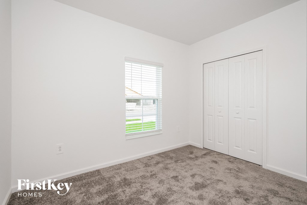 a bedroom with carpet and a window and a closet