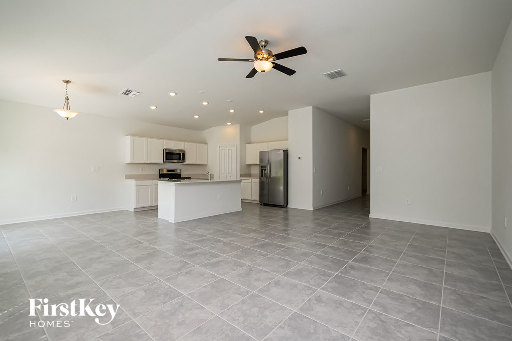 an empty living room and kitchen with a ceiling fan