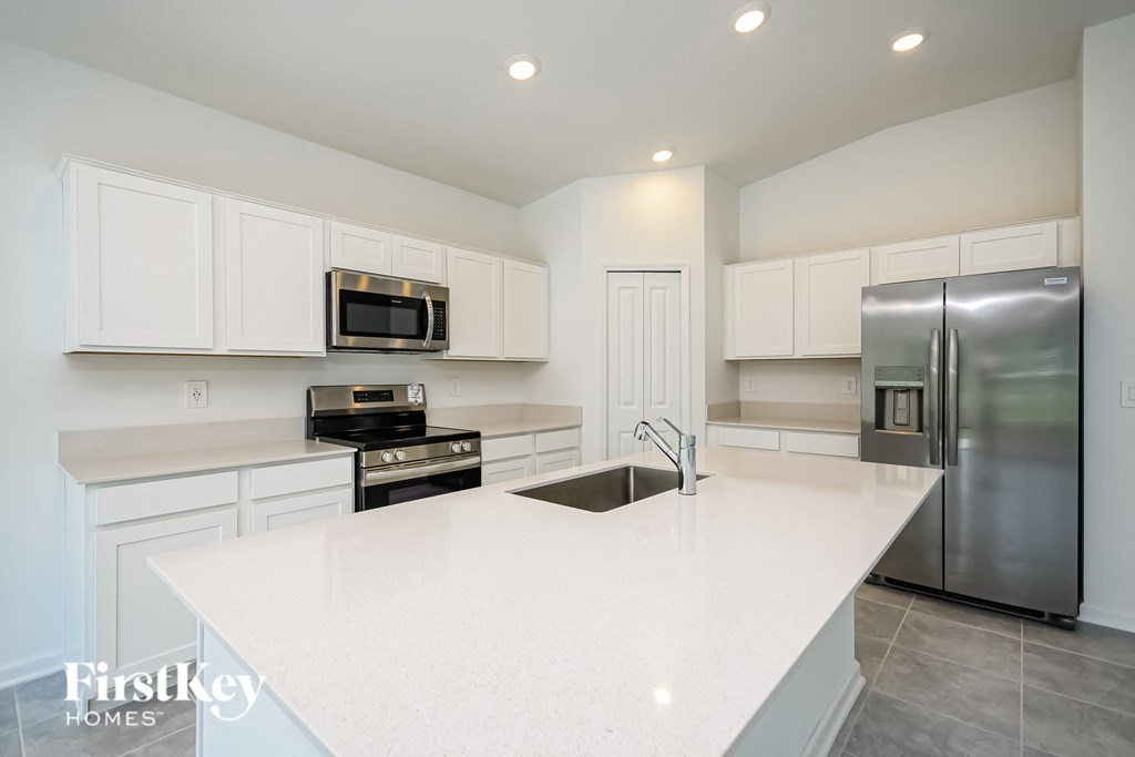 a white kitchen with stainless steel appliances and white counter tops