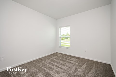 a bedroom with white walls and carpet and a window