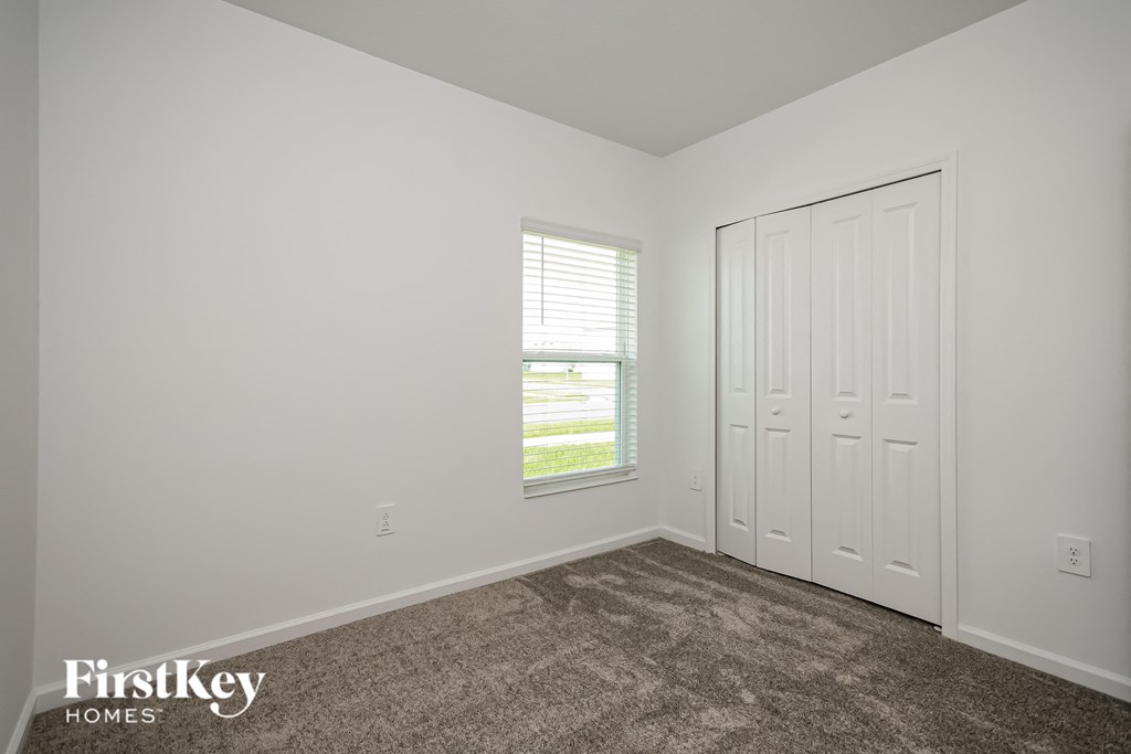 a bedroom with carpet and a closet and a window