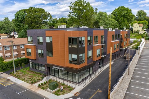 A modern apartment building with a parking lot in front.