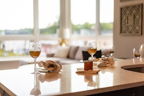 A table with two glasses of wine and a lit candle on it.