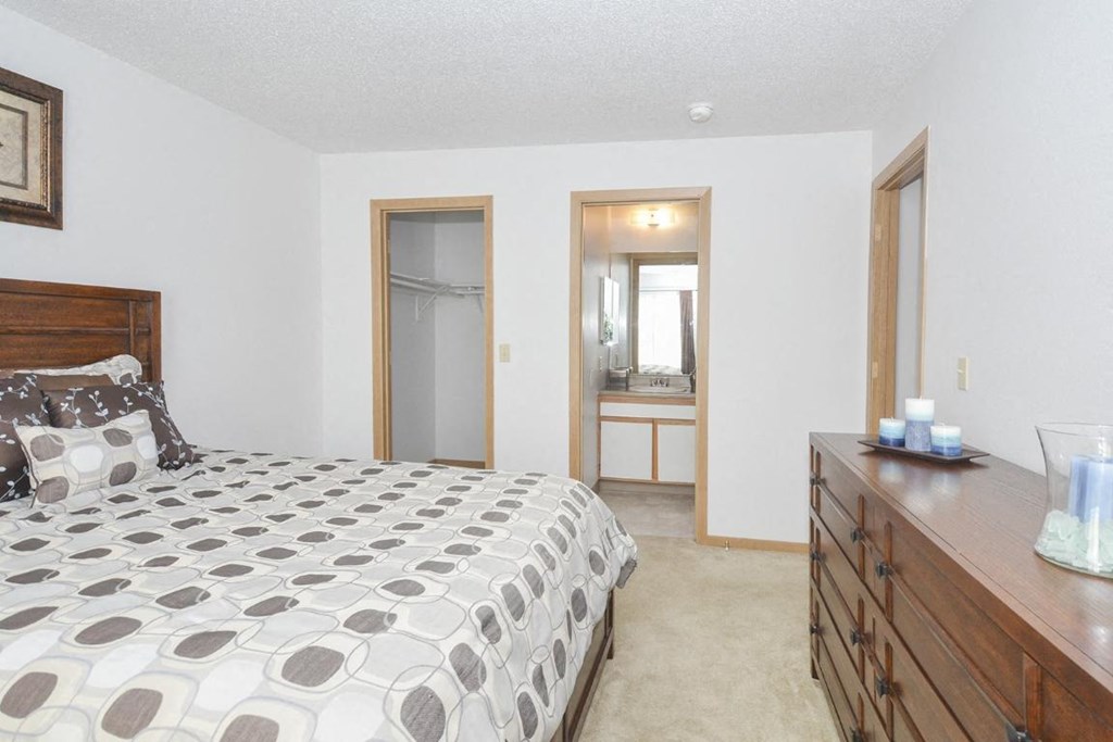 a bedroom with a bed and a dresser and a bathroom