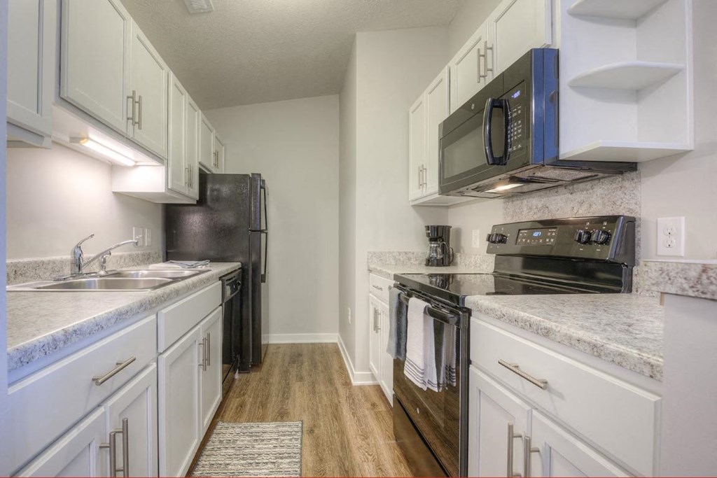 a kitchen with white cabinets and black appliances
