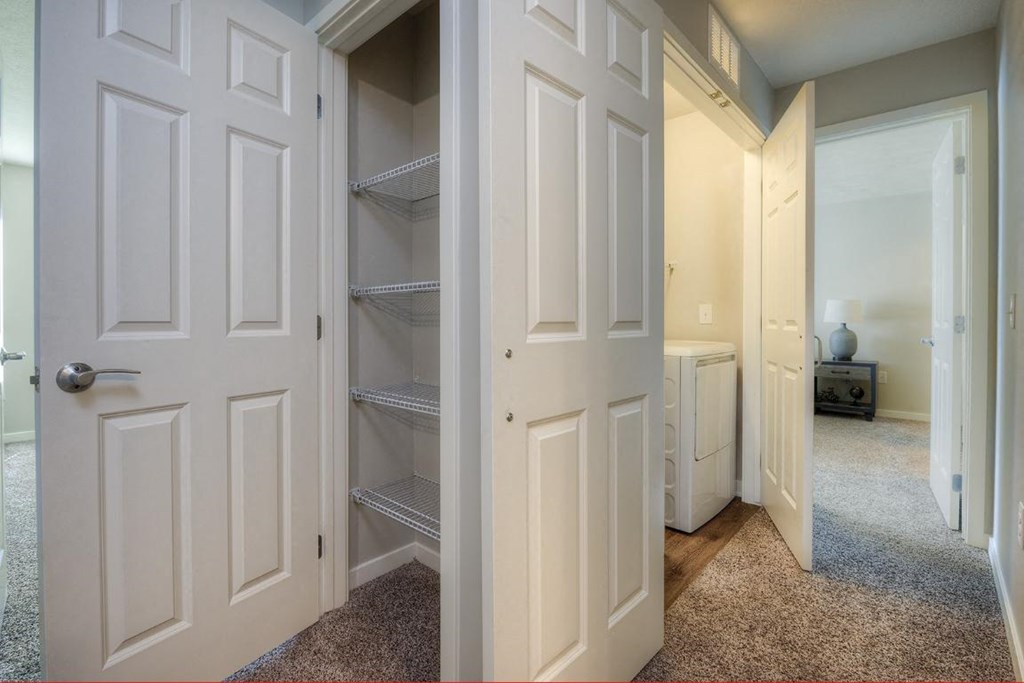 a walk in closet with white doors and a closet door open
