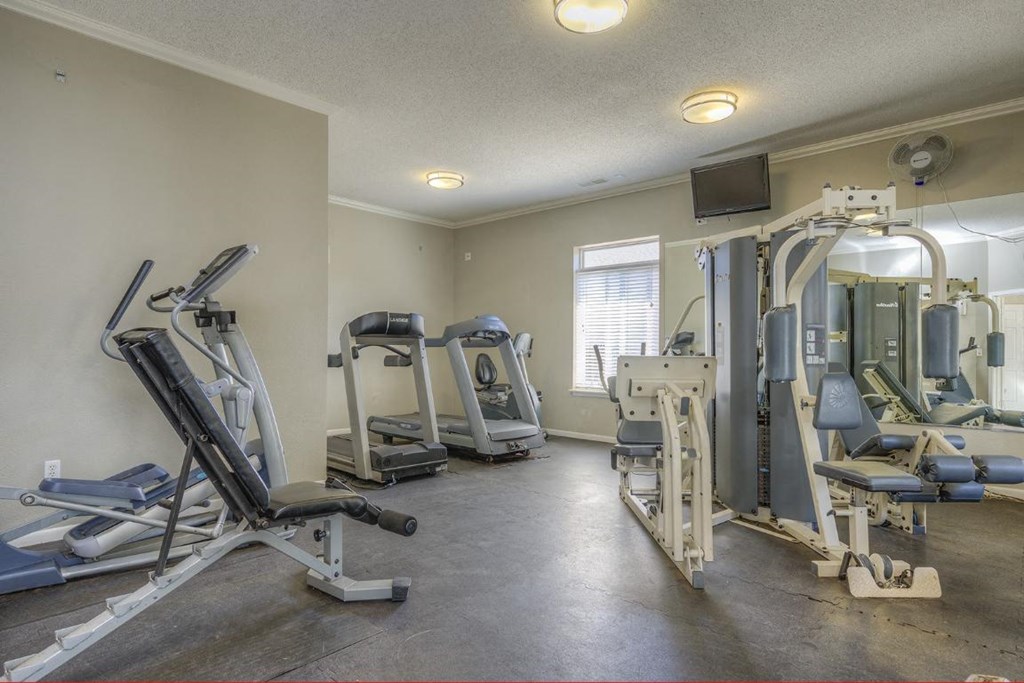 a gym with various machines and weights in a room with a window