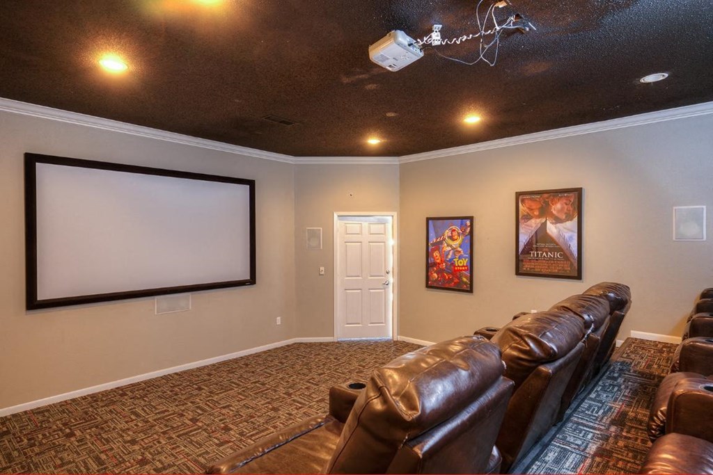 a theater room with leather couches and a projector screen