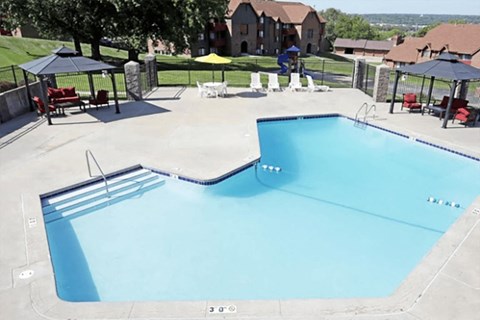 an empty swimming pool with tables and umbrellas at a resort
