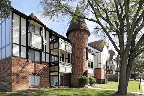 the exterior of a brick apartment building with a tall tower