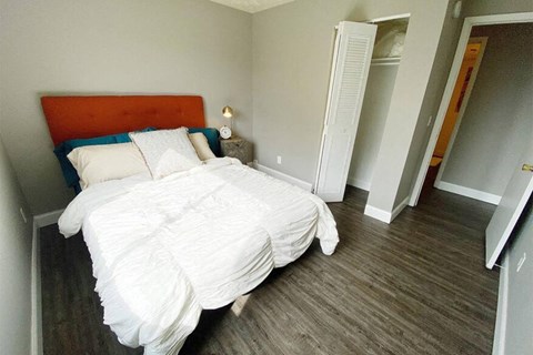 a bedroom with a white bed and a wooden floor