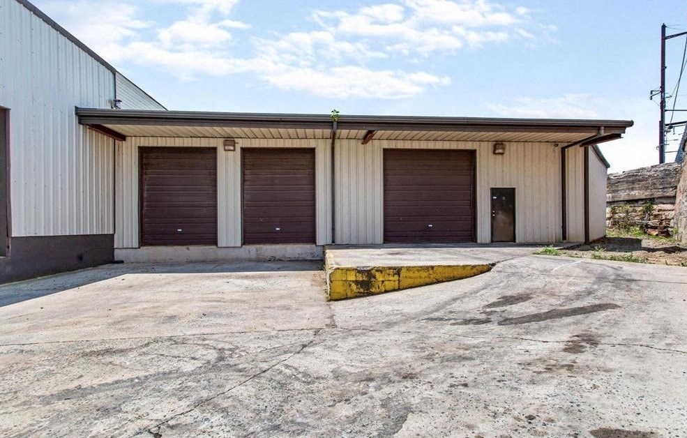 A large industrial building with a concrete ground and a yellow line.