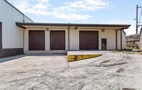 A large industrial building with a concrete ground and a yellow line.